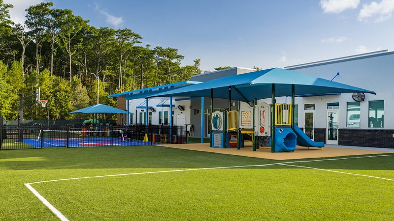 Expansive outdoor playground with turf field and covered play areas